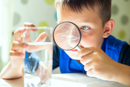 boy looking at water with magnifying glass